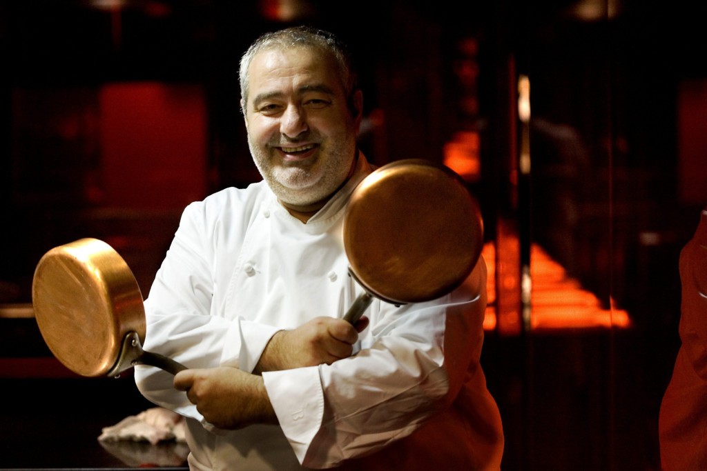 Chef Santi Santamaria with two pans in hand in cooking uniform
