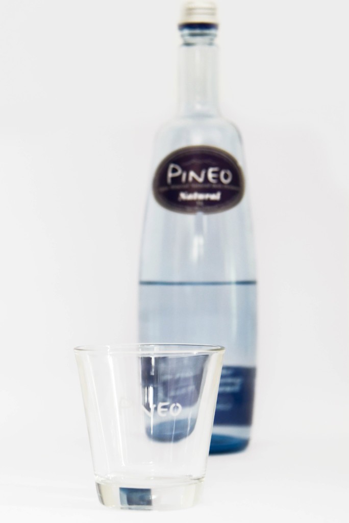 Bouteille d’eau de Pineo avec verre au premier plan