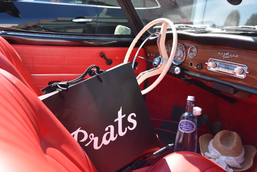 The inside of an old timer car with a bag of prats and a bottle of pineo water