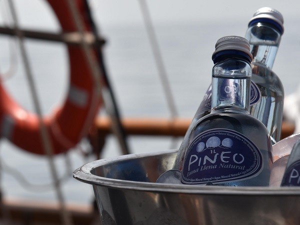 The durable glass bottles of Pineo in an ice bucket on a classic sailing ship during Sotogrande